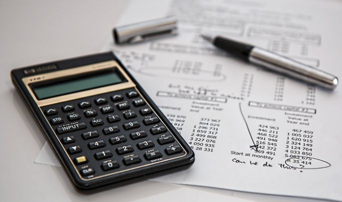 A calculator on top of a pile of paper files