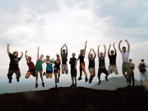 group of students jumping at the top of a mountain