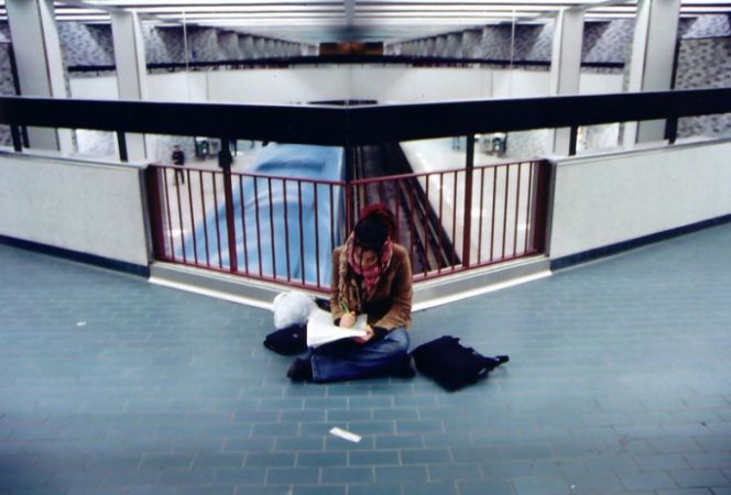 Student writing on the floor of a building